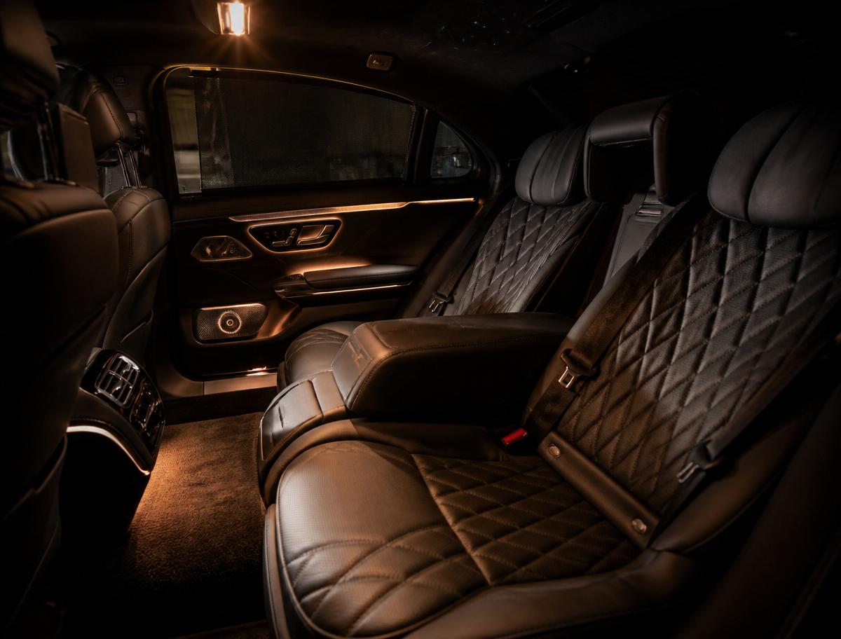 Quilted leather rear cabin of a luxury sedan lit with warm amber ambient lighting